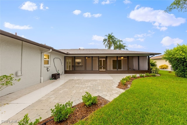 back of property featuring a yard, a patio area, and a sunroom