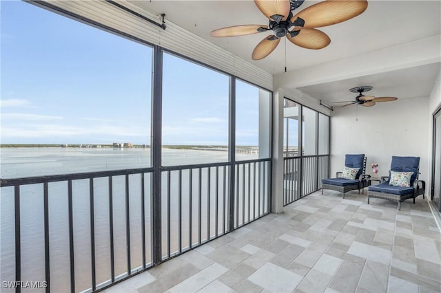 sunroom with a water view and ceiling fan