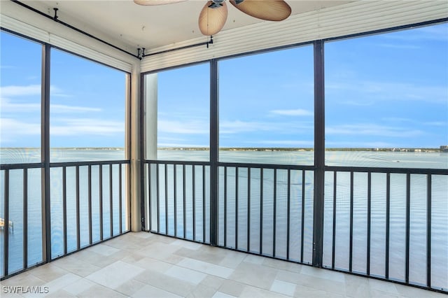 unfurnished sunroom with a water view and ceiling fan