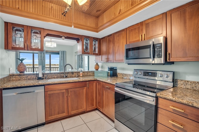 kitchen with light stone countertops, stainless steel appliances, sink, light tile patterned floors, and wooden ceiling