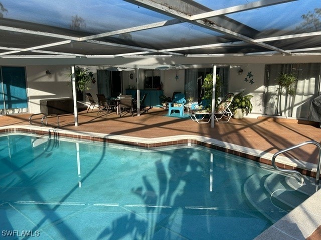 view of swimming pool with glass enclosure and a patio