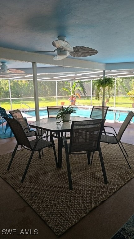 sunroom featuring ceiling fan, a healthy amount of sunlight, and a swimming pool