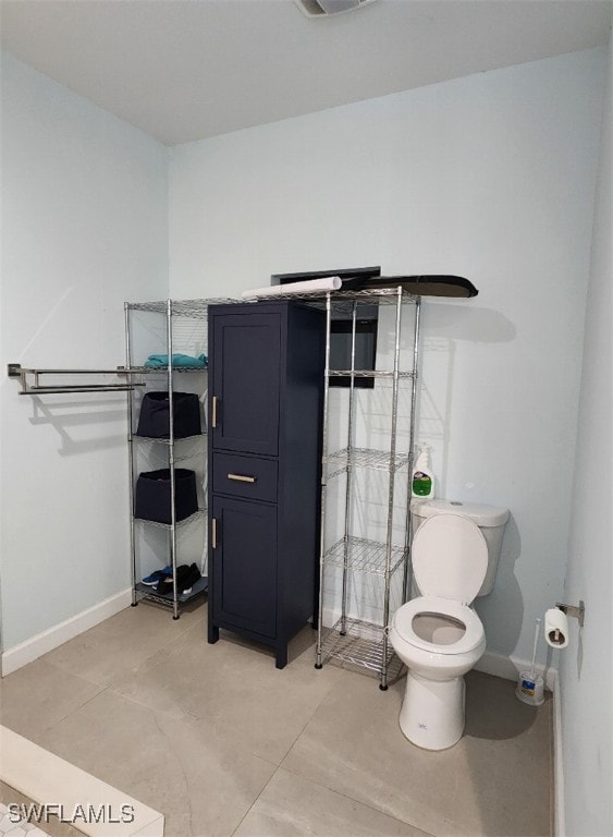 bathroom featuring a shower with door, toilet, and tile patterned floors