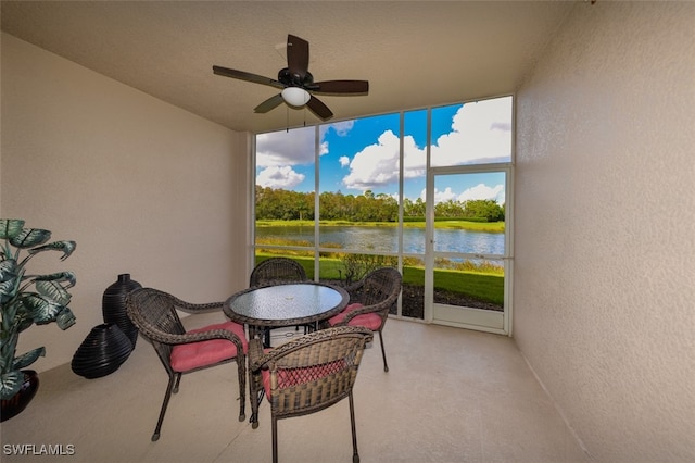 sunroom / solarium featuring a water view and ceiling fan