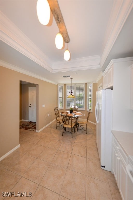 tiled dining room featuring ornamental molding and a raised ceiling