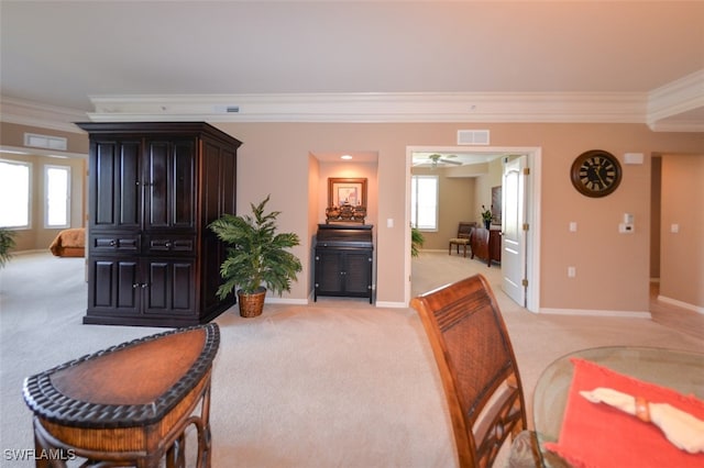 interior space featuring ornamental molding, ceiling fan, light colored carpet, and a healthy amount of sunlight