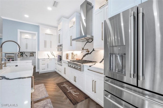 kitchen with white cabinets, wall chimney range hood, and appliances with stainless steel finishes