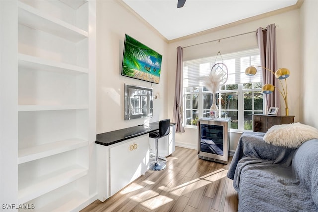 sitting room with light hardwood / wood-style floors, built in features, a wealth of natural light, and crown molding