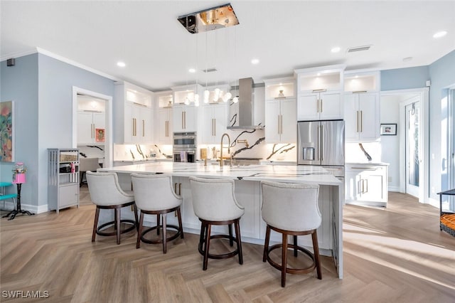 kitchen with wall chimney exhaust hood, a spacious island, sink, pendant lighting, and white cabinets