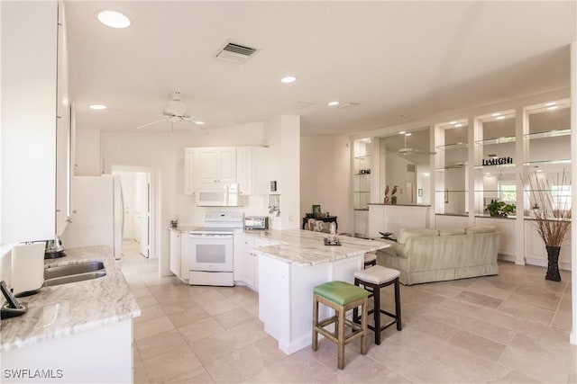 kitchen featuring a kitchen breakfast bar, white appliances, visible vents, and white cabinets