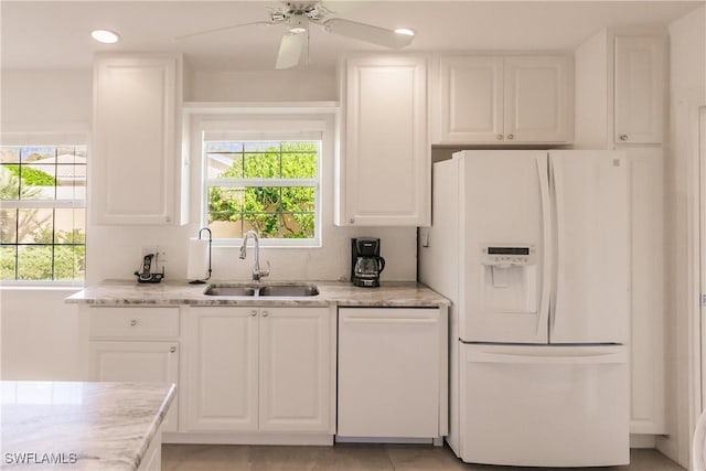 kitchen with white appliances, white cabinets, and a sink