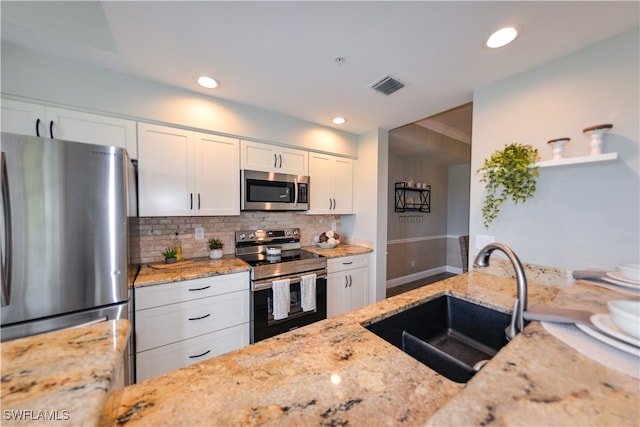 kitchen with stainless steel appliances, sink, white cabinets, light stone counters, and tasteful backsplash