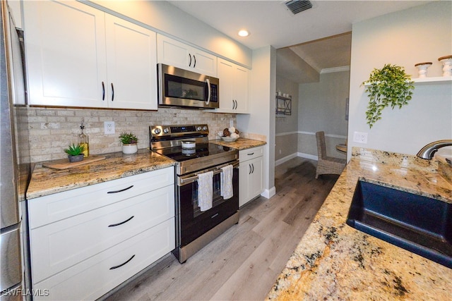 kitchen featuring light stone countertops, sink, white cabinetry, light hardwood / wood-style floors, and stainless steel appliances