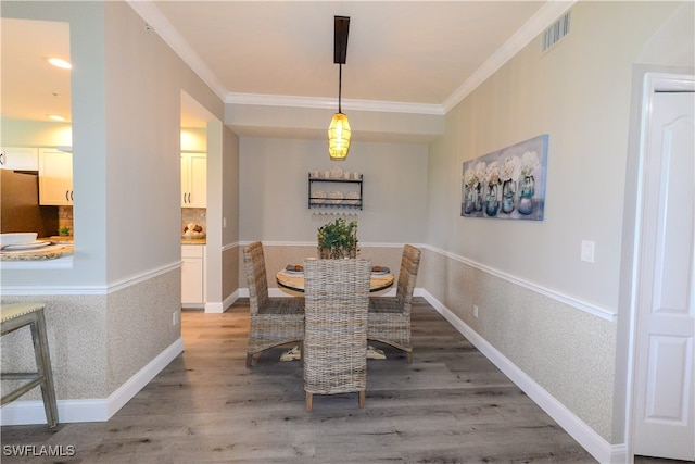 dining room with crown molding and hardwood / wood-style flooring