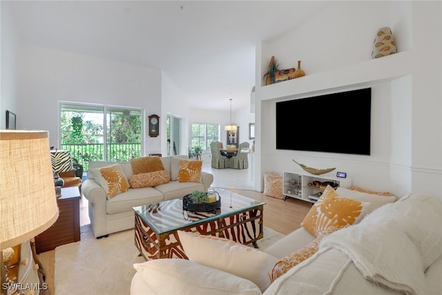 living room with light hardwood / wood-style flooring, a towering ceiling, and a healthy amount of sunlight