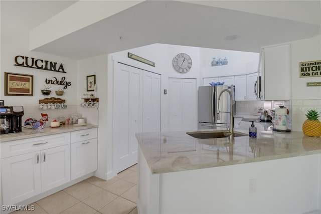 kitchen featuring light stone counters, light tile patterned floors, white cabinetry, stainless steel appliances, and decorative backsplash