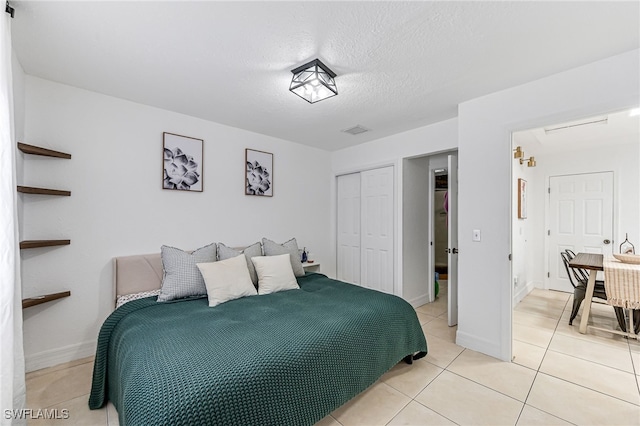 tiled bedroom with a closet and a textured ceiling