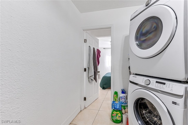 laundry area with light tile patterned flooring and stacked washing maching and dryer