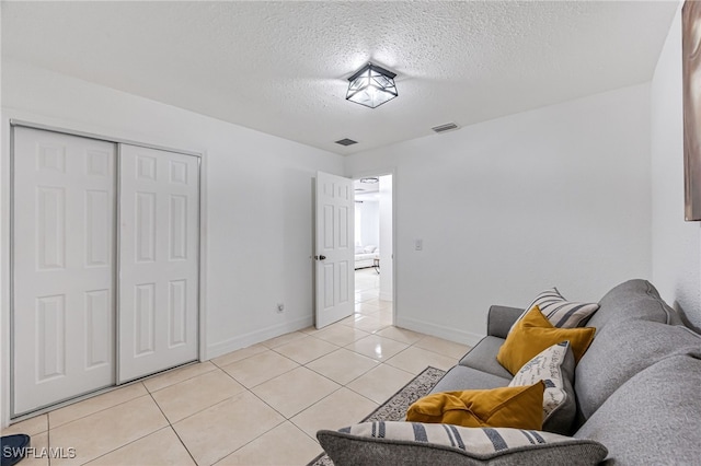 living area with a textured ceiling and light tile patterned floors