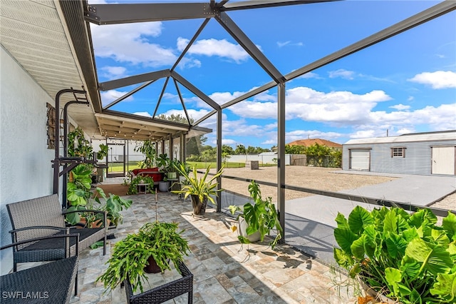 view of patio / terrace featuring glass enclosure and an outbuilding