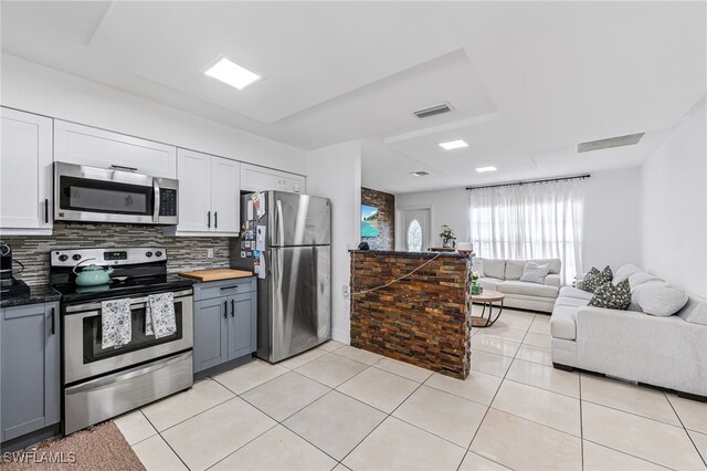 kitchen with white cabinets, light tile patterned floors, gray cabinets, appliances with stainless steel finishes, and decorative backsplash