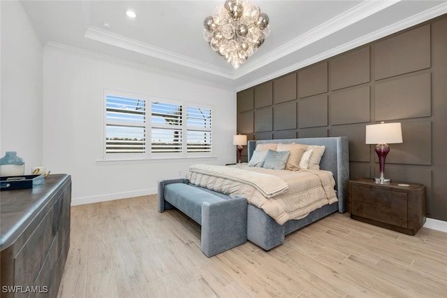 bedroom featuring light hardwood / wood-style floors, a raised ceiling, ornamental molding, and a chandelier