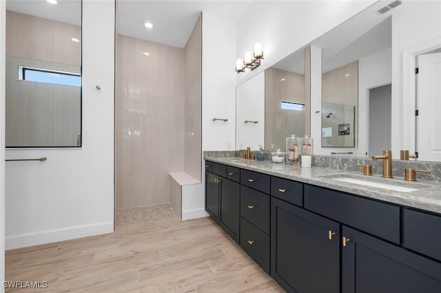 bathroom featuring vanity, hardwood / wood-style floors, and a tile shower