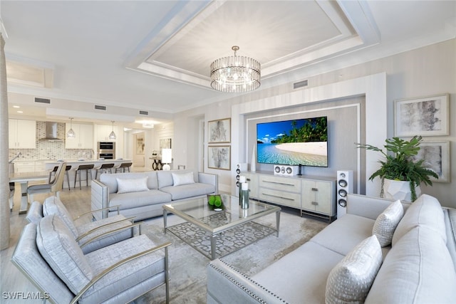 living room with a notable chandelier and a raised ceiling