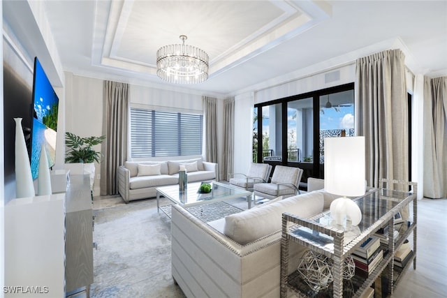 living room with a tray ceiling, a notable chandelier, and light hardwood / wood-style floors