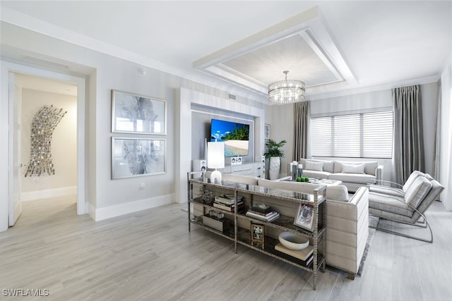 living room with a notable chandelier, a raised ceiling, and light hardwood / wood-style flooring