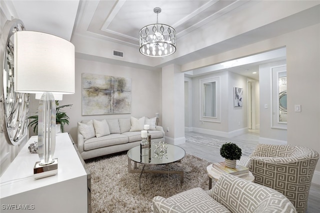 living room with a raised ceiling, hardwood / wood-style floors, and a chandelier