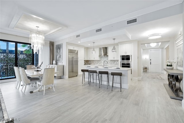 dining space featuring a tray ceiling, light hardwood / wood-style flooring, and sink