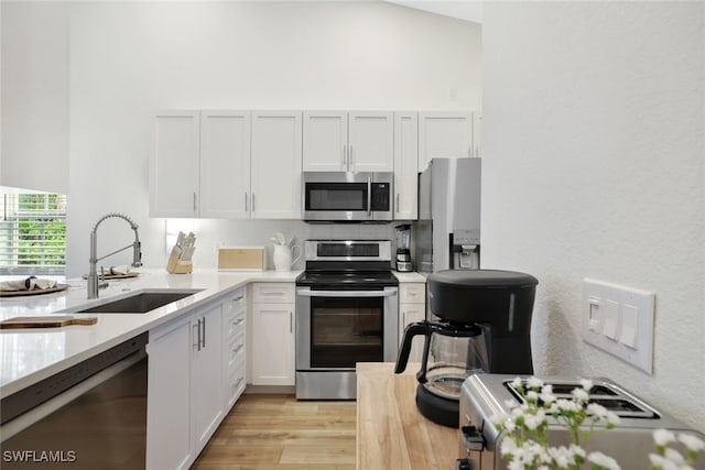 kitchen featuring white cabinets, sink, light hardwood / wood-style flooring, decorative backsplash, and appliances with stainless steel finishes