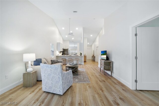 living room with light wood-type flooring and high vaulted ceiling