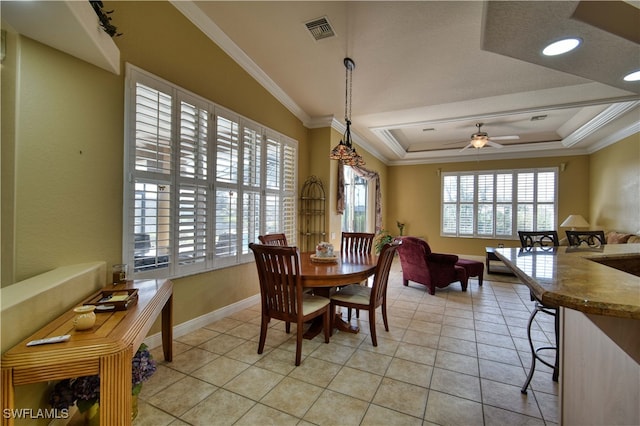 tiled dining space featuring a raised ceiling, ornamental molding, and ceiling fan