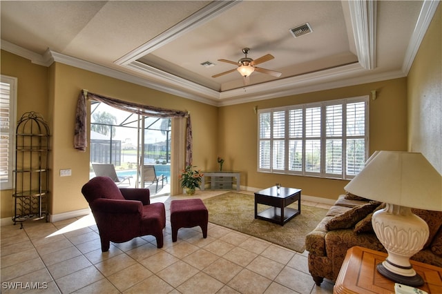 sitting room with light tile patterned flooring, a raised ceiling, crown molding, and ceiling fan