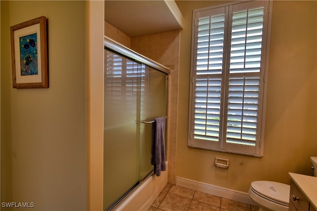 full bathroom featuring shower / bath combination with glass door, vanity, tile patterned flooring, and toilet