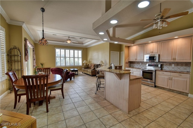 kitchen with ceiling fan, a breakfast bar area, stainless steel appliances, light stone countertops, and hanging light fixtures