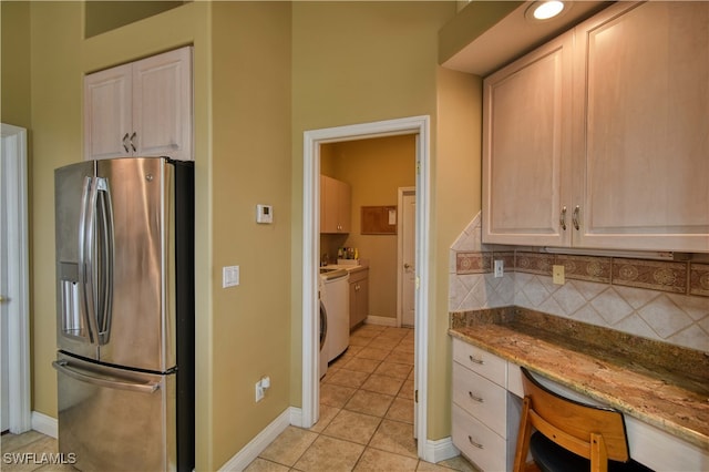 kitchen with built in desk, decorative backsplash, light stone countertops, stainless steel fridge with ice dispenser, and light tile patterned floors