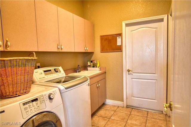 clothes washing area with washing machine and dryer, cabinets, sink, and light tile patterned floors