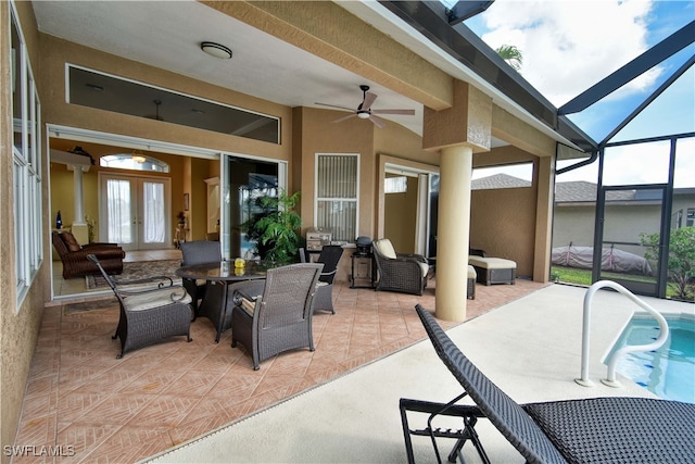 view of patio with ceiling fan, outdoor lounge area, french doors, and glass enclosure