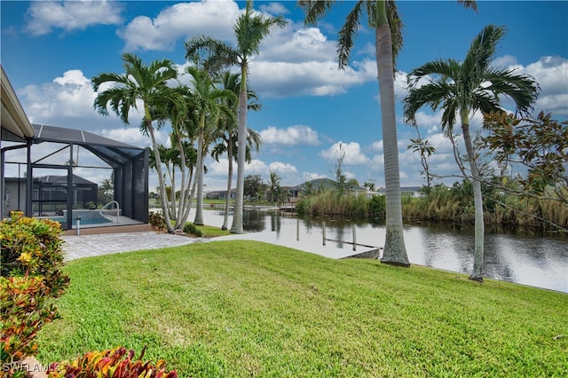 view of yard featuring glass enclosure, a water view, and a patio area