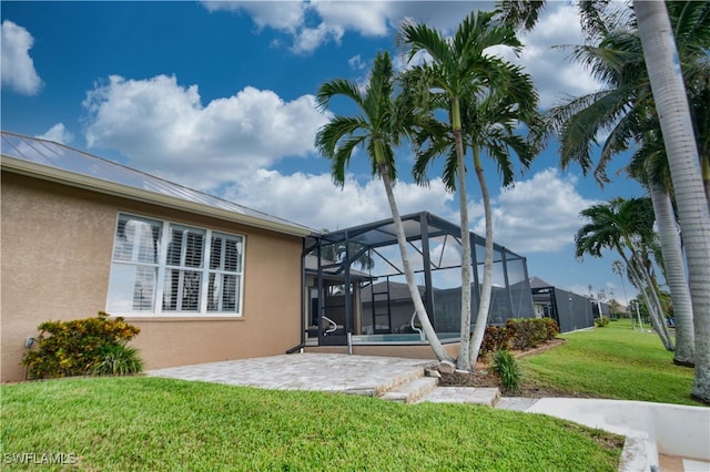 rear view of house featuring a lawn, a patio area, and a lanai