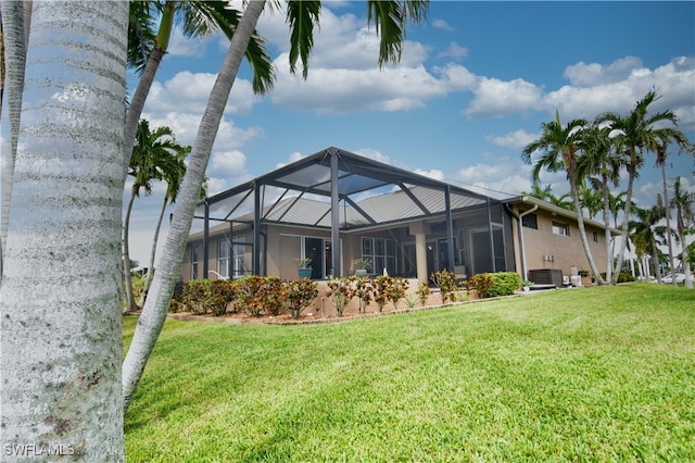 rear view of house with a yard, central AC unit, and a lanai