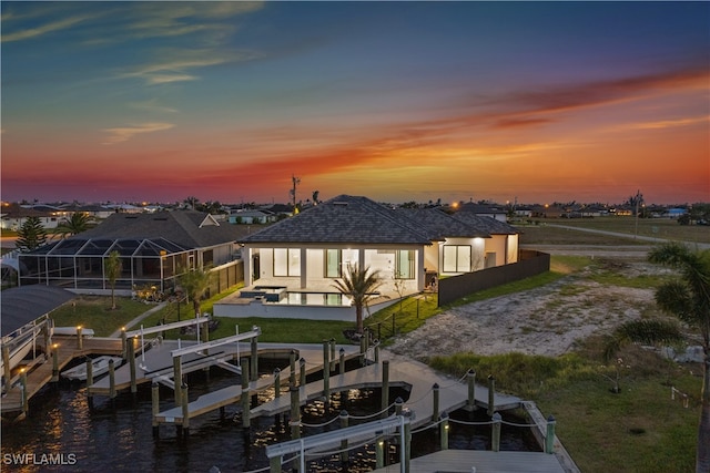 back house at dusk featuring a patio area, a water view, and glass enclosure