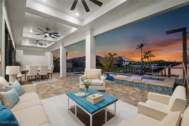 patio terrace at dusk featuring ceiling fan and an outdoor hangout area