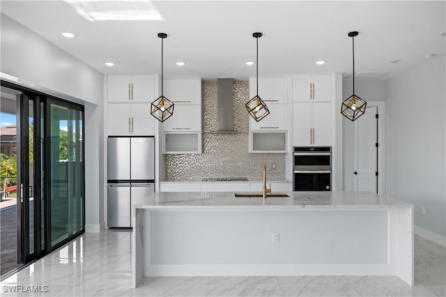 kitchen with wall chimney exhaust hood, white cabinets, stainless steel appliances, and sink