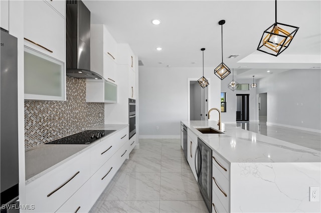 kitchen with wall chimney range hood, sink, appliances with stainless steel finishes, and hanging light fixtures