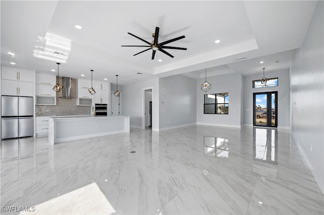 unfurnished living room with french doors, a tray ceiling, and ceiling fan