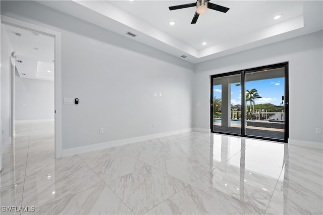 spare room with ceiling fan and a raised ceiling